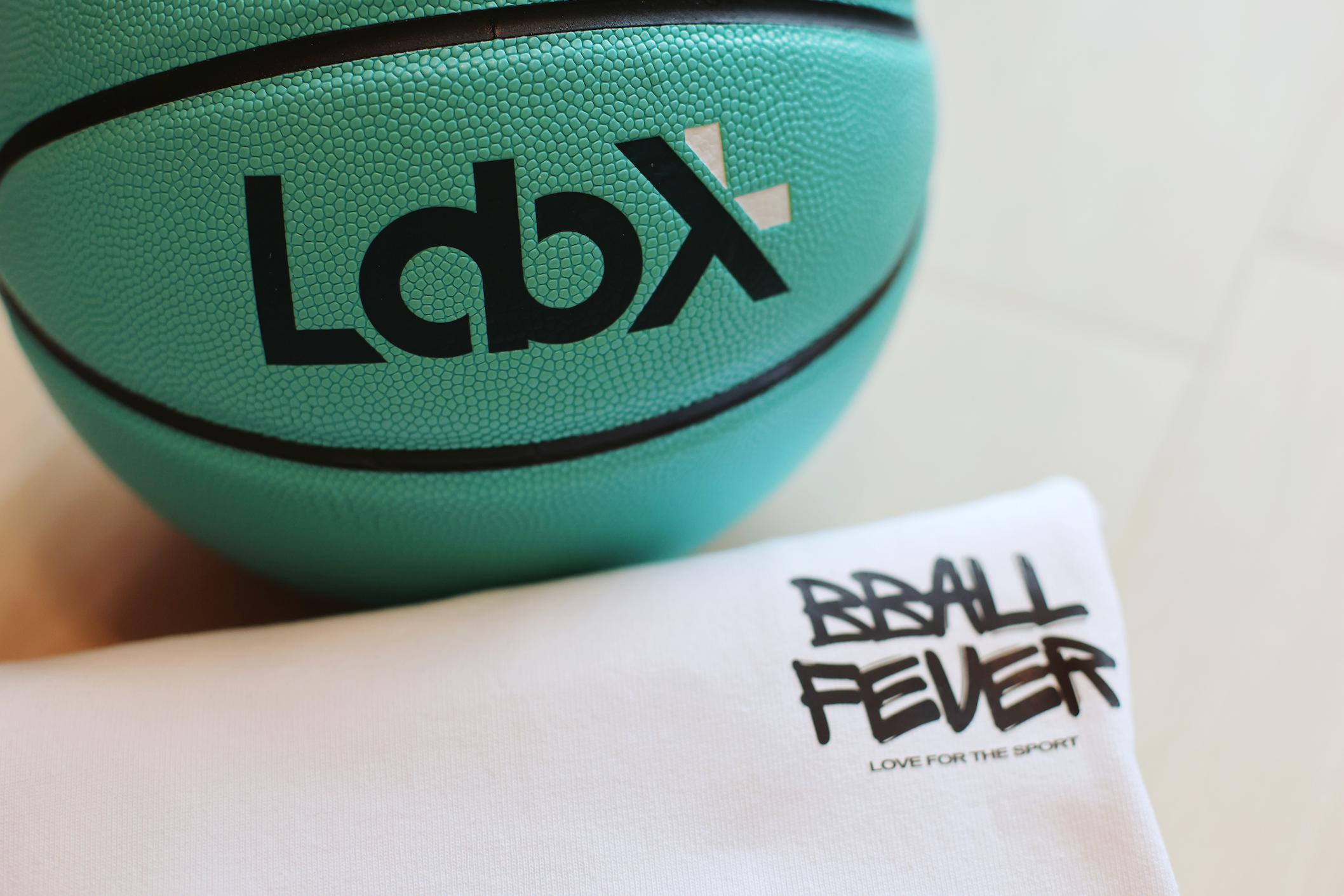 Basketball Fever Tee. Basketball themed T-shirt with unique piece designed by Asian artist. Photo taken next to a LabXPlus basketball.